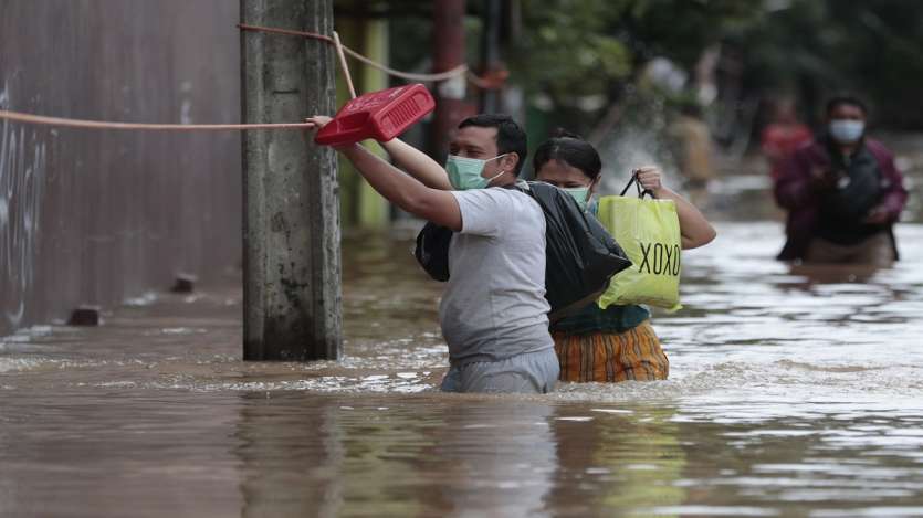 A man holds onto a safety line installed at a flooded neighborhood following heavy rains in Jakarta, Indonesia.