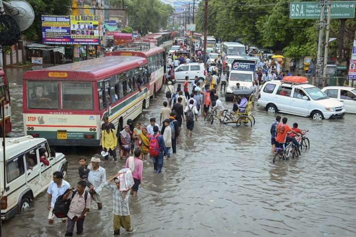 Pedestrians wade across a waterlogged road after monsoon
